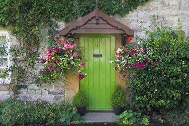 Vibrant green front door surrounded by colorful flowers and lush greenery.