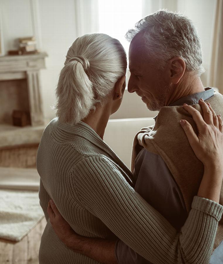 Elderly couple embracing in a cozy home setting, symbolizing equity release support.