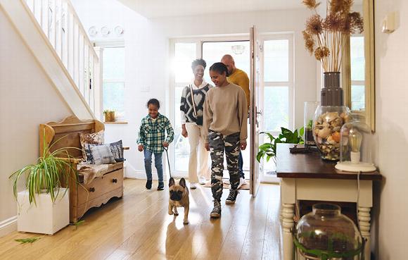 Family entering a bright hallway with a small dog, showcasing a welcoming home atmosphere.