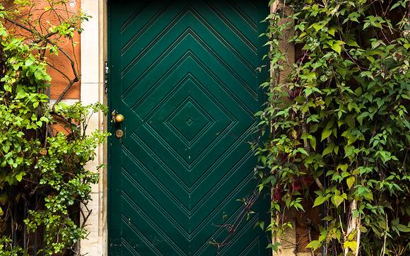 Green door surrounded by lush green vines and foliage.