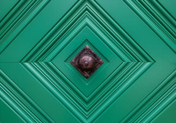 Green decorative door panel with a diamond pattern and ornate metal knocker.
