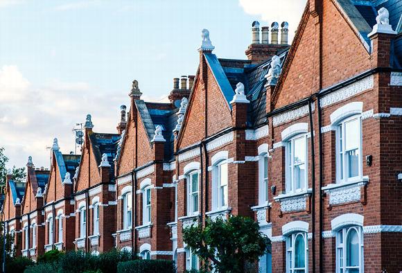 Row of red brick residential houses with prominent gables and white accents.