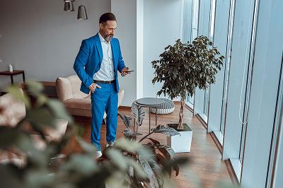 Professional man in a blue suit using a smartphone in a modern office space.